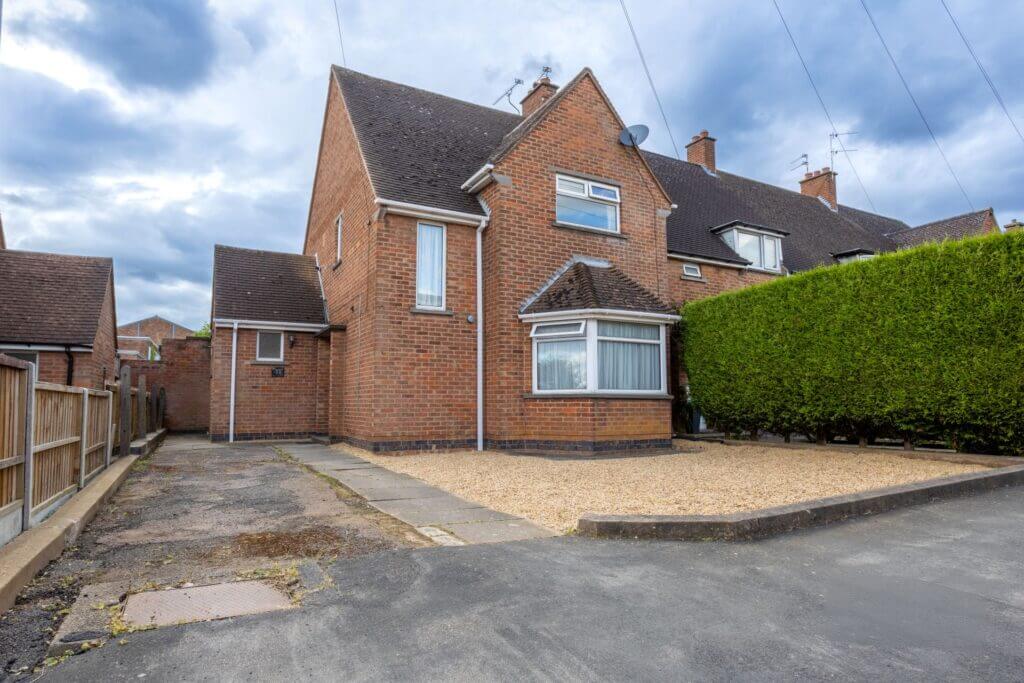 a brick house with a hedge in front of it